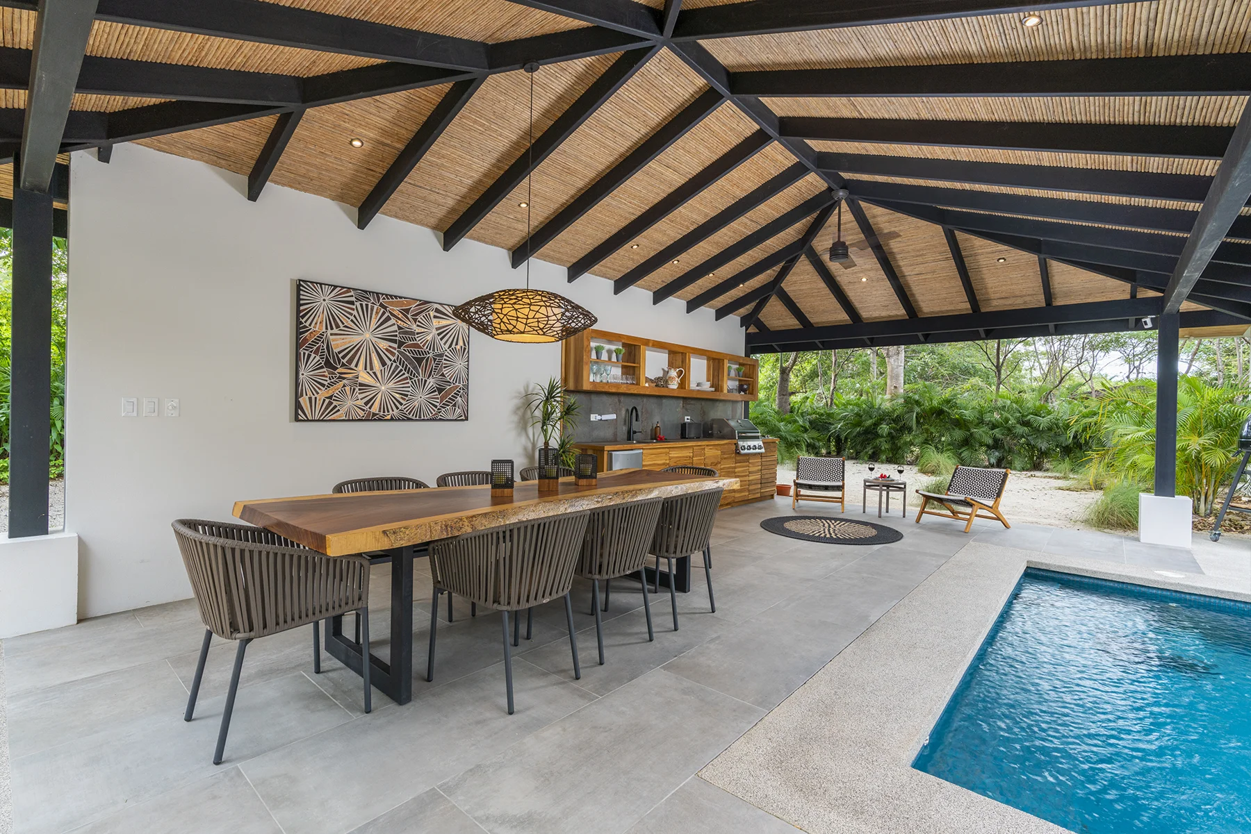 RG69 covered poolside pavilion with exposed roof beams, dining table and bar