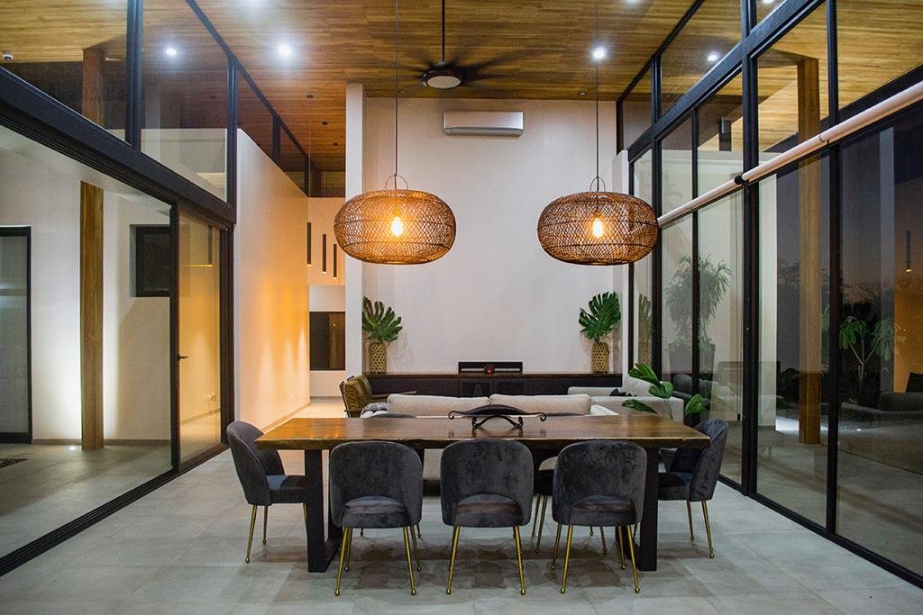 Dining room at night, with woven pendant lights and views into the courtyard